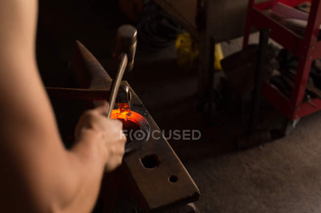 Gros plan de fer à cheval de moulage de forgeron femelle dans l'usine — Photo de stock