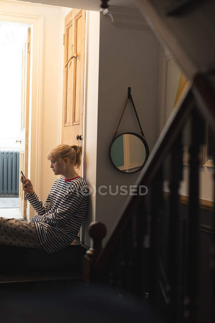Вид збоку жінки на дому за допомогою мобільного телефону — стокове фото