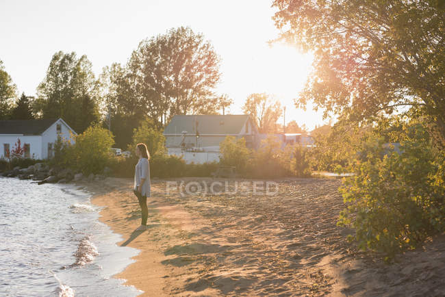 Женщина, гуляющая по пляжу в солнечный день — стоковое фото