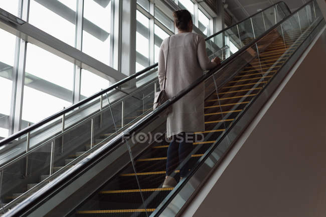 Задний вид женщины, поднимающейся на эскалаторе на железнодорожном вокзале — стоковое фото