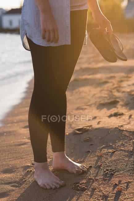 Низкая часть женщины, держащейся на пляже — стоковое фото