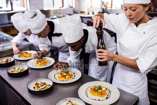 Група шеф-кухаря прикрашає їжу на тарілках — стокове фото