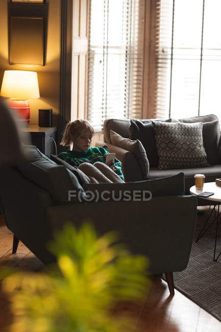 Woman using mobile phone on sofa in living room at home — Stock Photo