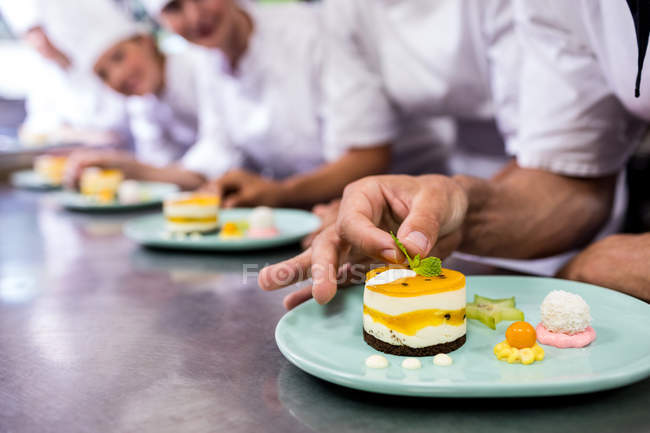 Gros plan du chef garnissant le dessert dans une assiette — Photo de stock