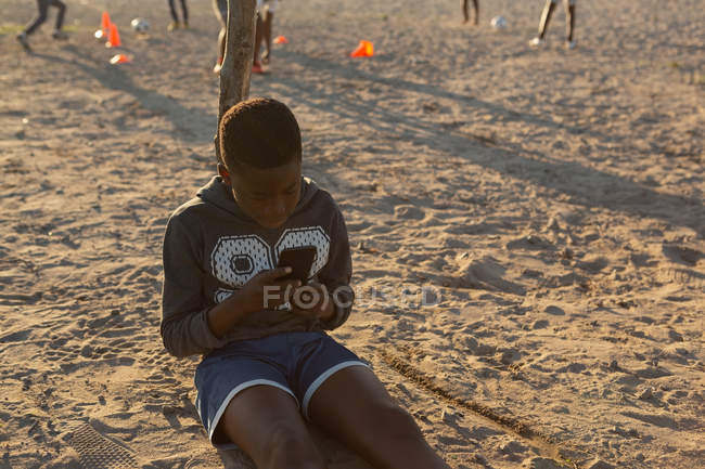 Kind benutzt Handy an einem sonnigen Tag in der Erde — Stockfoto