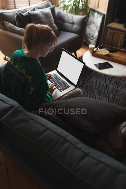 Mujer usando portátil en la sala de estar en casa - foto de stock