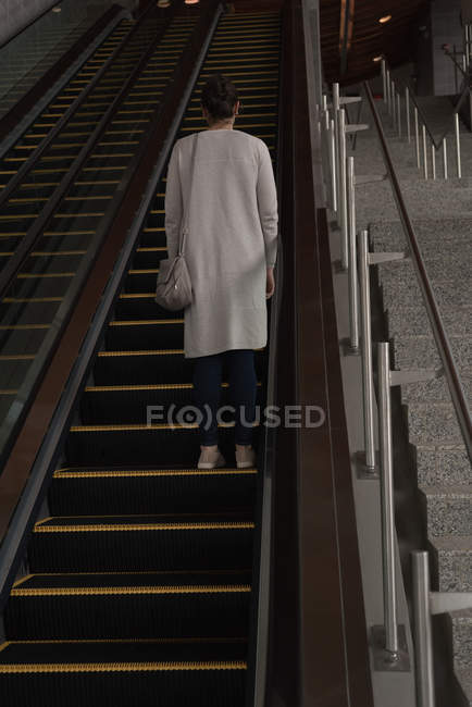 Vista posteriore della donna che sale sulla scala mobile alla stazione ferroviaria — Foto stock