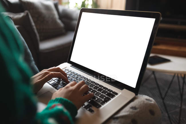 Primer plano de la mujer que usa el ordenador portátil en la sala de estar en casa - foto de stock
