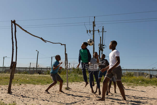 Bambini che giocano a calcio nel terreno in una giornata di sole — Foto stock