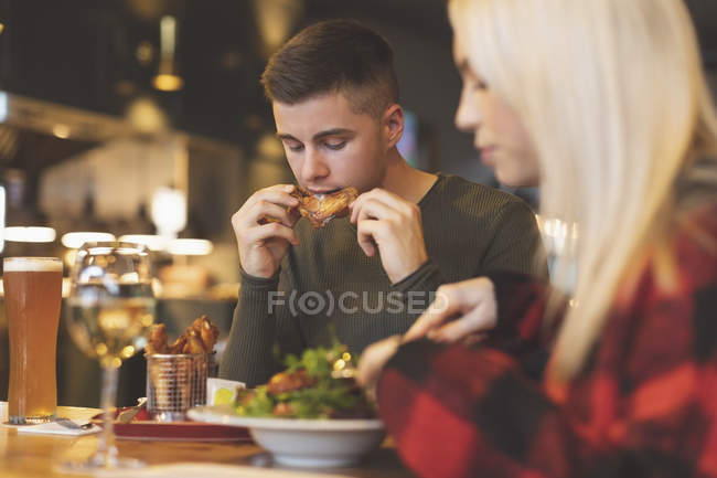 Jovem casal comer comida no restaurante — Fotografia de Stock