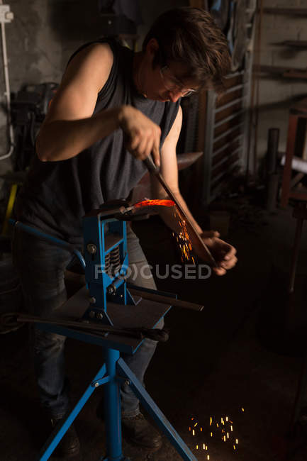 Fer à cheval de mise en forme de forgeron féminin attentif dans l'usine — Photo de stock