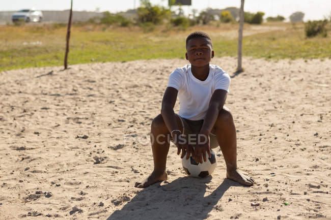 Portrait of boy sitting on football in the ground — Stock Photo