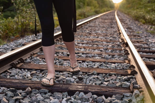 Partie basse de la femme marchant sur une voie ferrée — Photo de stock