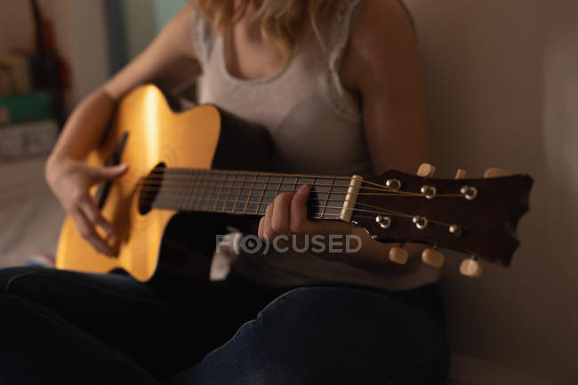 Mittelteil der Frau spielt zu Hause im Schlafzimmer Gitarre — Stockfoto