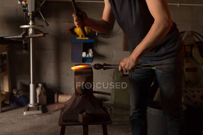 Mid section of female metalsmith molding horseshoe in factory — Stock Photo
