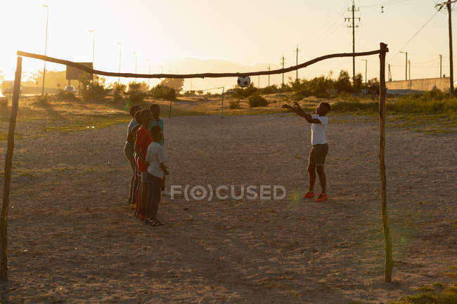 Enfants jouant avec le football dans le sol au crépuscule — Photo de stock