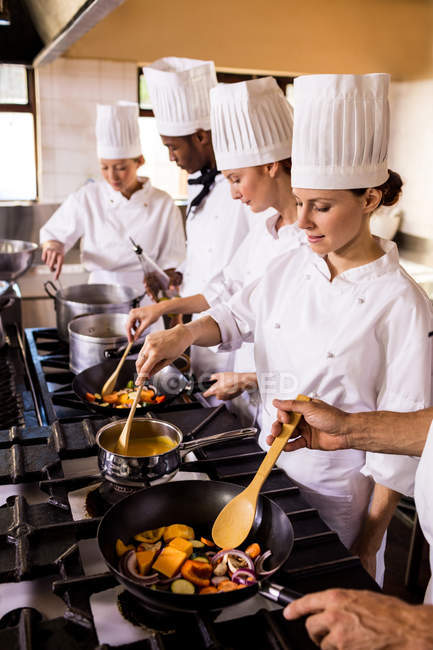 Group of chef preparing food in kitchen — Stock Photo