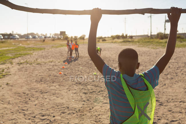 Rear view of boy hanging on goal post in the ground — Stock Photo