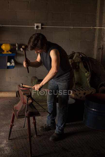 Attentive female metalsmith molding horseshoe in factory — Stock Photo