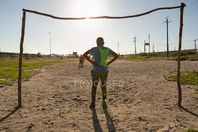 Visão traseira do menino em pé no poste de gol no chão — Fotografia de Stock