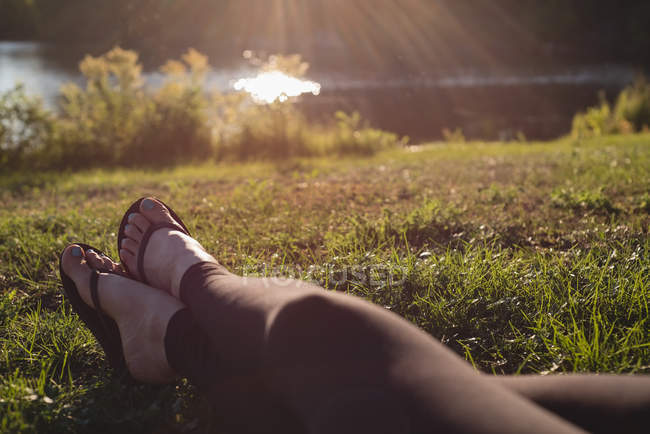 Low section of woman relaxing near riverside — Stock Photo