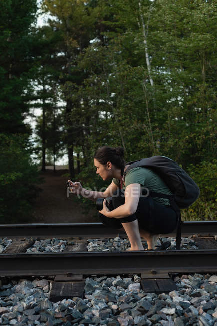 Mulher clicando fotos com telefone celular na trilha ferroviária — Fotografia de Stock