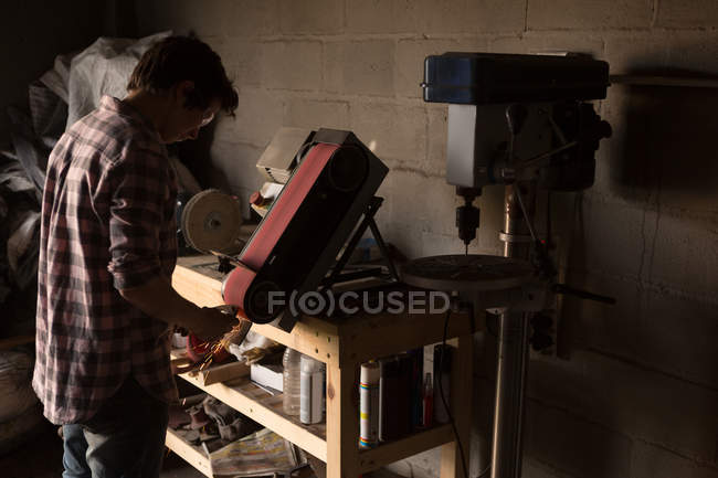 Ferreiro feminino usando máquina de afiar na fábrica — Fotografia de Stock