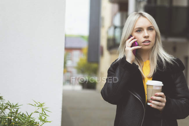 Preciosa mujer hablando en el teléfono móvil mientras toma café - foto de stock