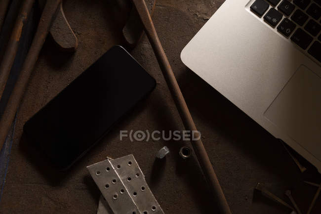 Close-up de laptop e telefone celular na fábrica de metaleiros — Fotografia de Stock