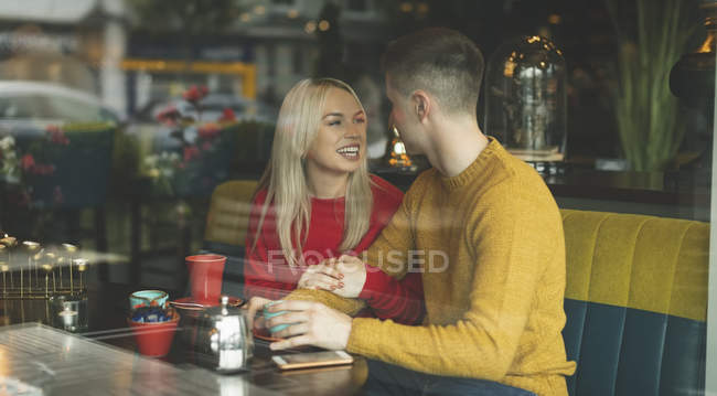 Pareja feliz interactuando entre sí en la cafetería - foto de stock
