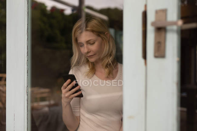 Belle femme utilisant un téléphone portable à la maison — Photo de stock