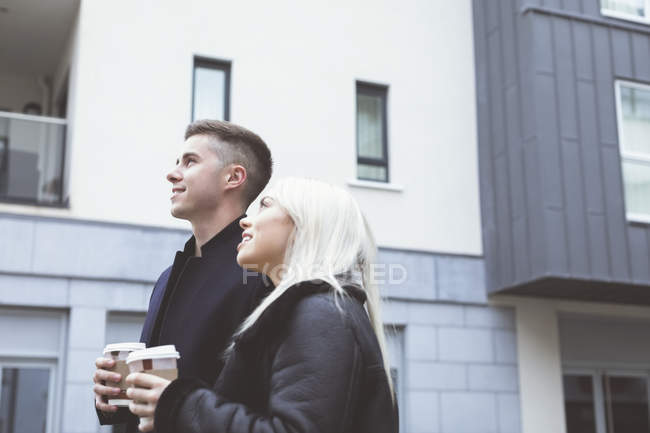 Couple souriant regardant loin tout en prenant un café — Photo de stock