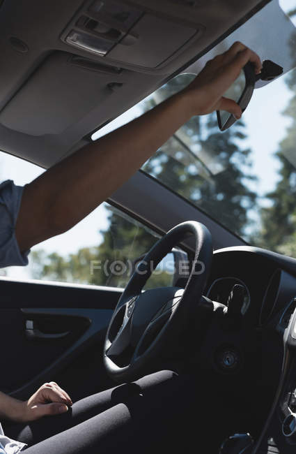 Середина жінки, що регулює дзеркало заднього виду в машині — стокове фото