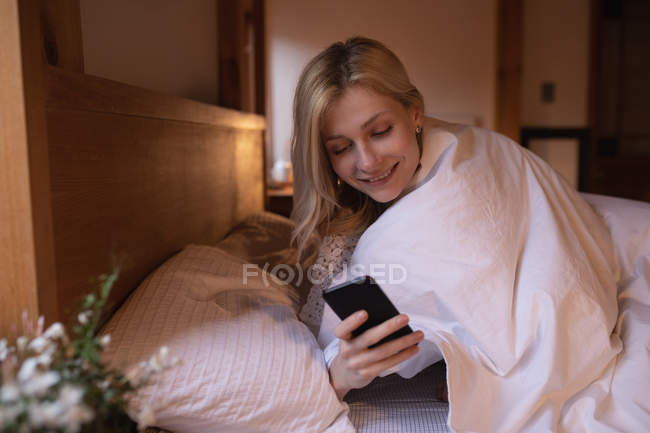 Woman using mobile phone in bedroom at home — Stock Photo