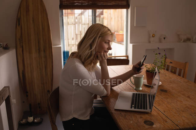 Mulher bonita usando telefone celular em casa — Fotografia de Stock