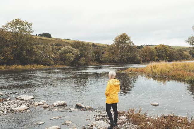 Вид ззаду жінки, що стоїть біля річки — стокове фото