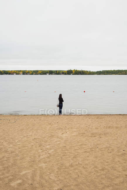 Vista posteriore della donna in piedi vicino al lungofiume — Foto stock