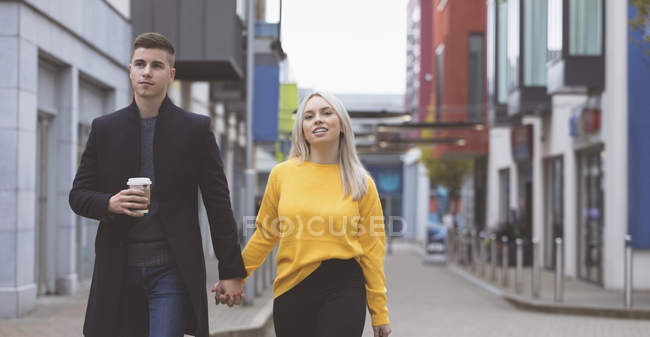 Jovem casal de mãos dadas e andando na rua — Fotografia de Stock