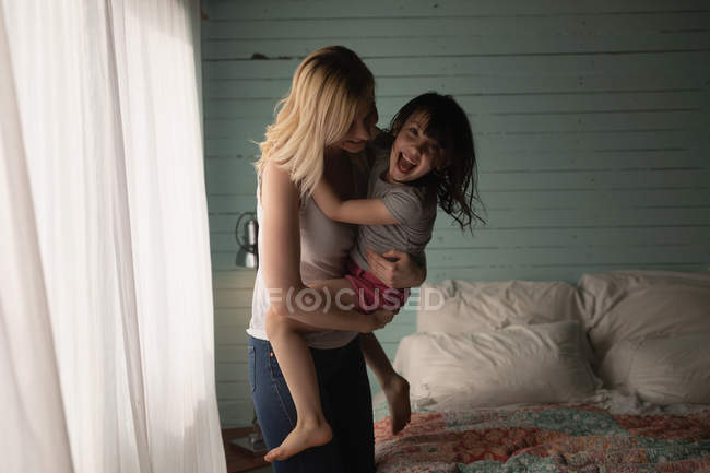 Mãe e filha abraçando uns aos outros no quarto em casa — Fotografia de Stock