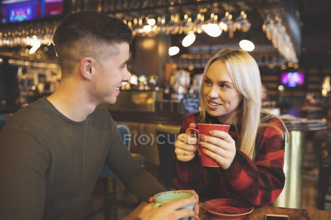 Casal interagindo enquanto toma café na cafetaria — Fotografia de Stock