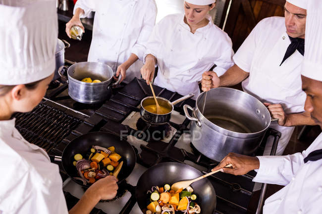 Группа шеф-поваров готовит еду на кухне — стоковое фото