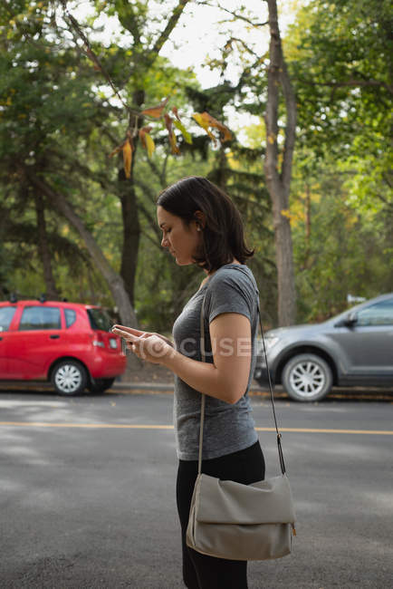 Frau benutzt Handy an einem sonnigen Tag auf der Straße — Stockfoto