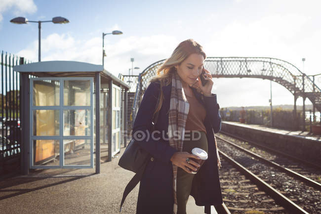 Вагітна жінка розмовляє по мобільному телефону на платформі на залізничній станції — стокове фото
