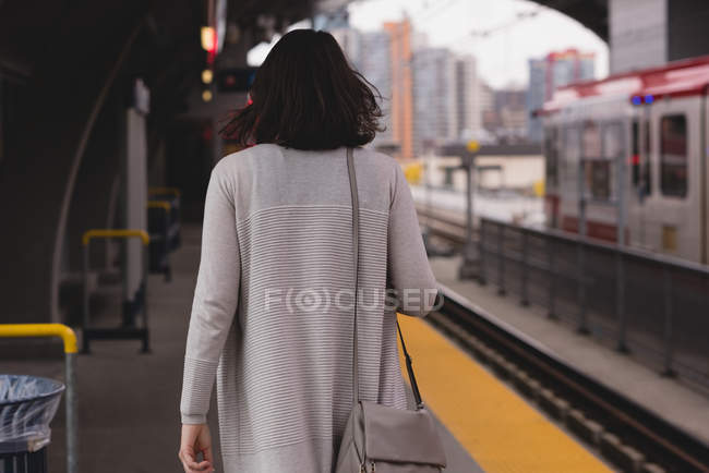 Вид сзади на женщину, идущую по платформе на вокзале — стоковое фото
