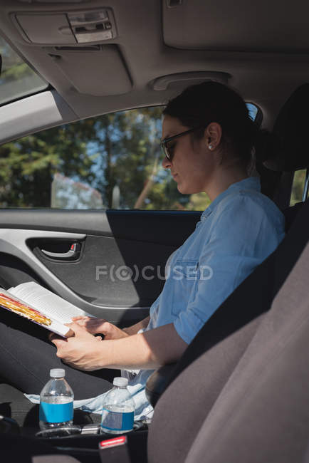 Belle femme lisant un livre dans une voiture — Photo de stock