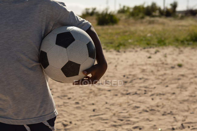 Sezione centrale del ragazzo che tiene il calcio nel terreno — Foto stock