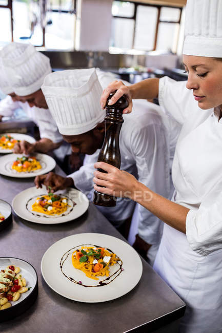Group of chef garnishing food on plates — Stock Photo