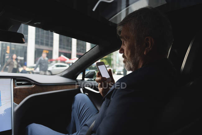Vue latérale de l'homme d'affaires parlant sur le téléphone mobile dans la voiture — Photo de stock
