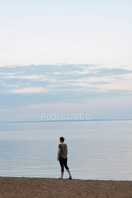 Donna che cammina sulla spiaggia al tramonto — Foto stock