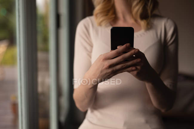 Mid section of woman using mobile phone at home — Stock Photo